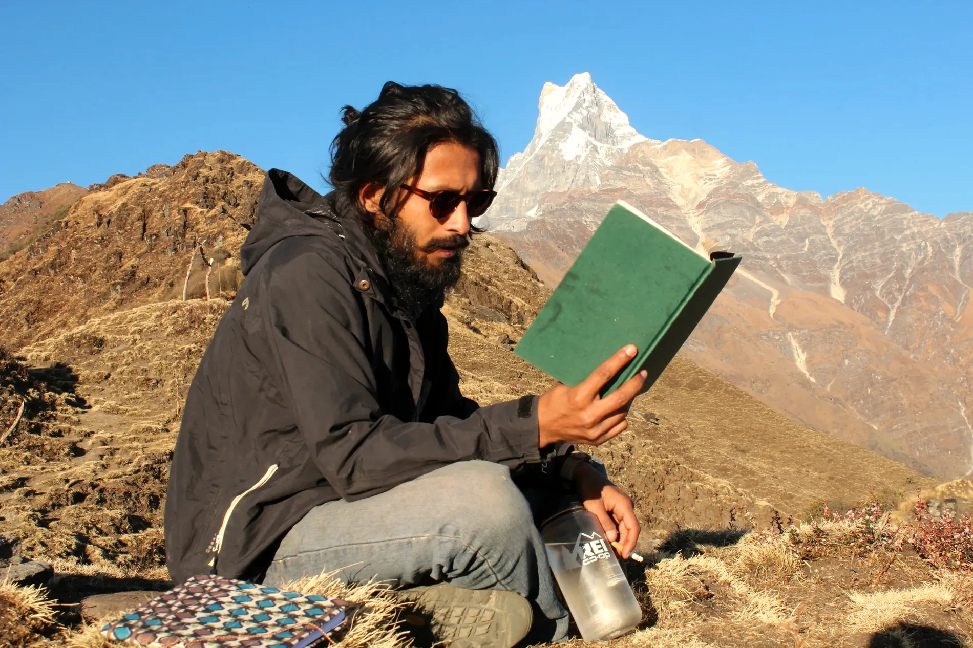 Khem Raj Pradhan reading on a mountain ridge below Machapuchare in the Nepal Himalaya
